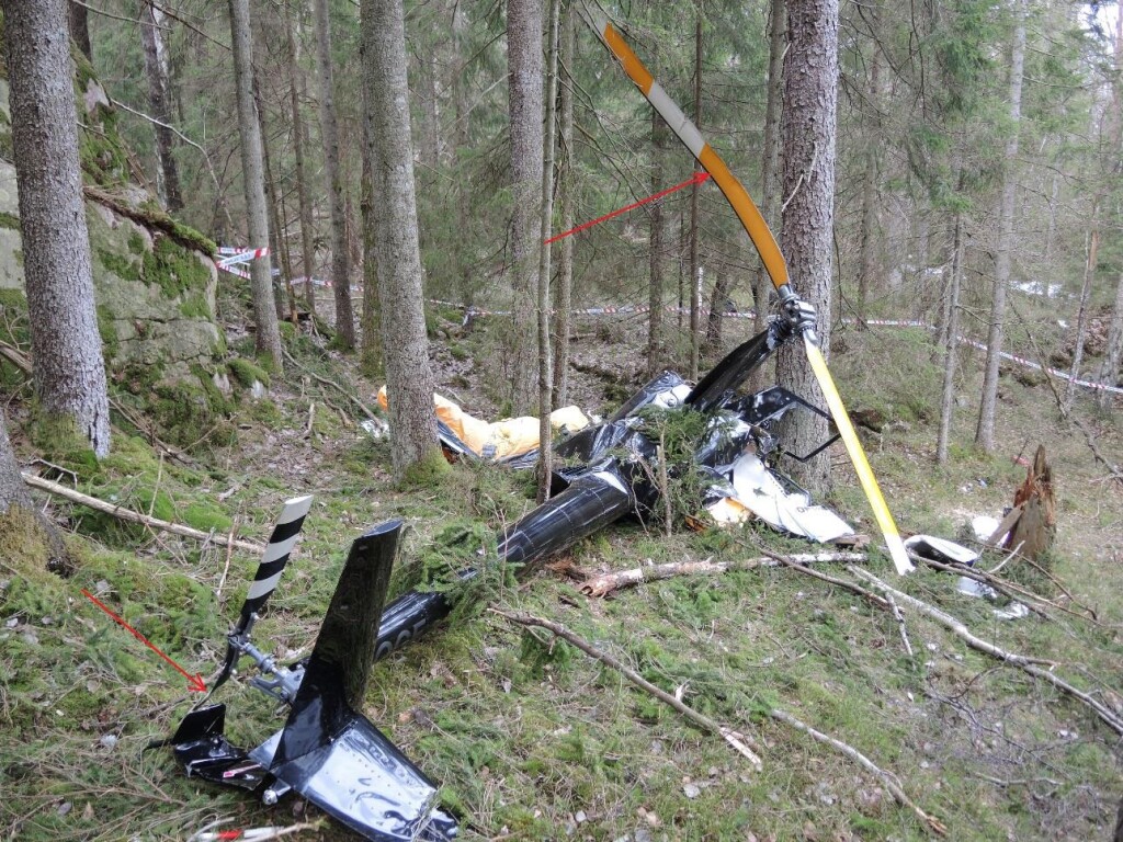 Robinson R44 LN-OGF: The accident site seen toward the northwest. The red arrows show a crack in one of the tail rotor blades and the bend in one of the main rotor blades (Credit: NSIA)