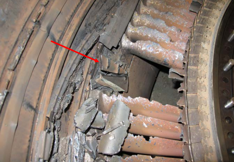 View from the rear of the location of the missing 3rd stage vane cluster with an arrow pointing to the piece of 3rd stage vane cluster inner shroud (Credit: P&W via NTSB)
