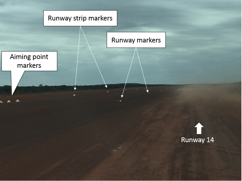 Darlot Airport runway 14 and left side of runway strip as viewed from the right seat of the aircraft with white frangible cones used as markers. Raised dust extends from the centre of the runway across the southern side of the runway strip. (Credit: ATSB/Pilot)